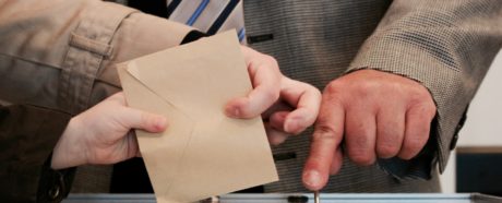 Man putting a voting slip into a ballot box.