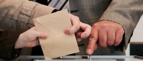 Man putting a voting slip into a ballot box.