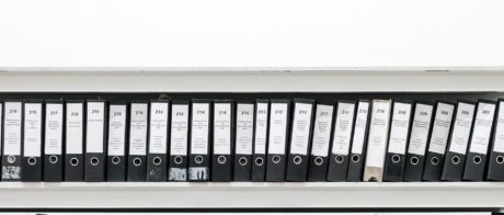 A cabinet full of filing lever arch folders on 4 shelves.