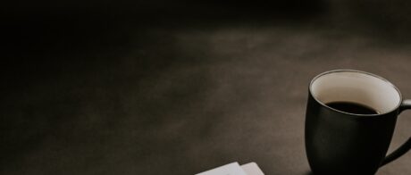 Cup of coffee next to papers on a desk.