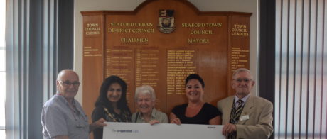 People in a row from Seaford Musical Theatre receiving a large cheque.
