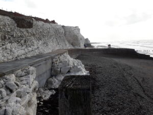 A photograph of Splash Point, a concrete path at the foot of cliff leading to a short curved pier out to sea