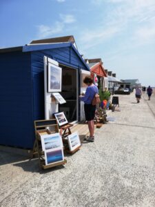 Row of beach huts selling goods and a person looking at pictures.