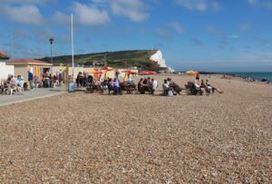 Martello Kiosk at Seaford seafront, people sitting on benches enjoying food and drink.