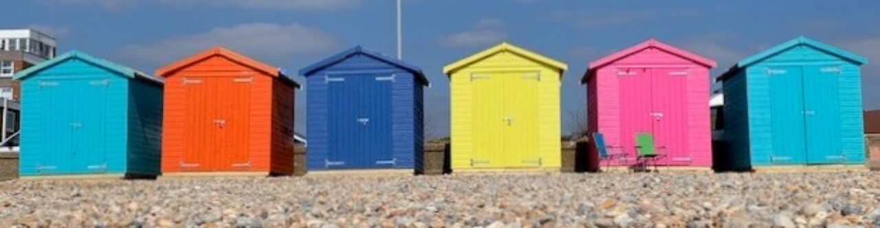a row of colourful beach huts on a sunny day with blue sky background