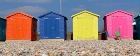 a row of colourful beach huts on a sunny day with blue sky background