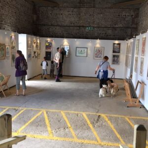 people inside barn at art exhibition looking at paintings