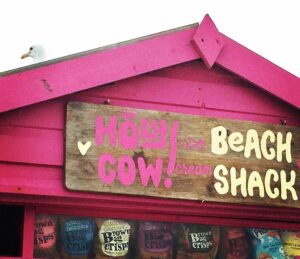 bright pink ice cream shack with Holy Cow Beach Shack inscription