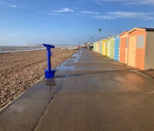 picture of blue telescope on seaford promenade in front of colourful beach huts