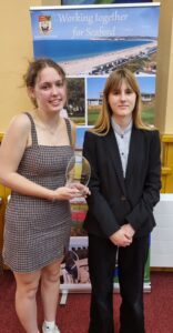 Two people holding a glass award with a banner in the background which read "Working Together for Seaford"