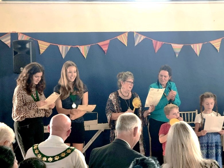 Four people standing and singing with bunting behind them