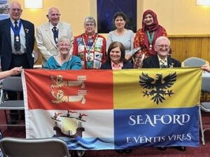 Seaford Town Council Mayors holding up the Seaford Town Flag in from of them.