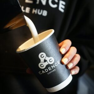 Disposable coffee cup with coffee being poured into it.