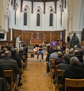 Ewan Hamilton playing guitar at the Carol Service.